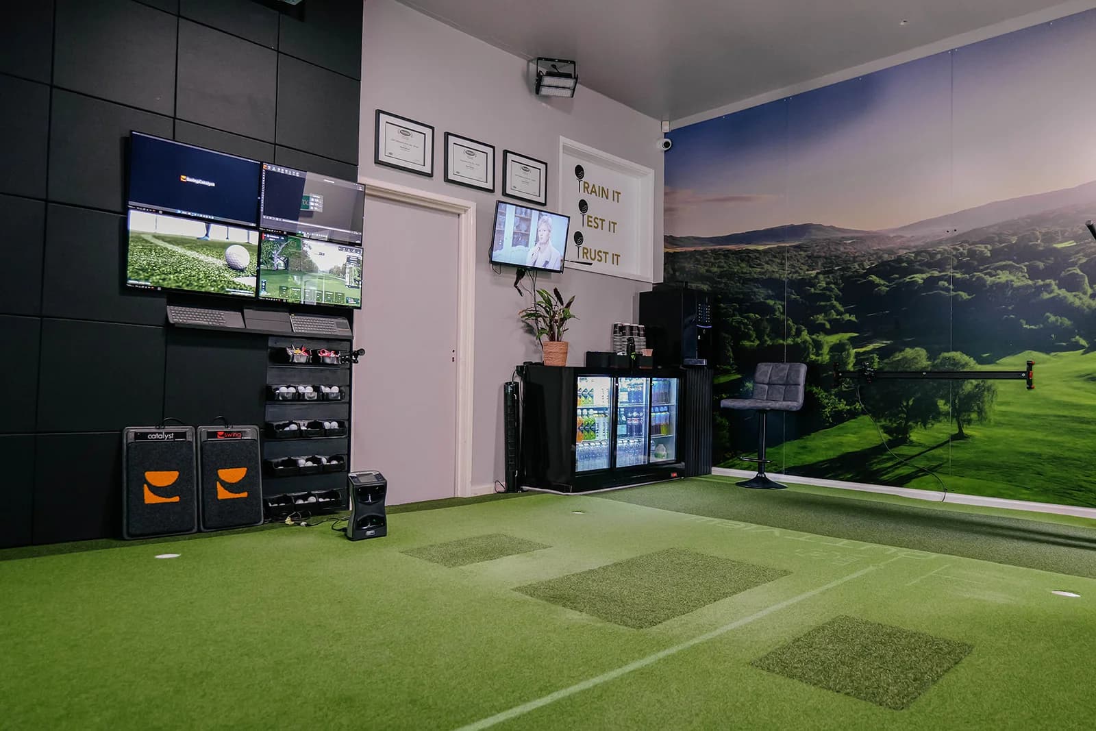 The SW:ING Studio bay: hitting mats on the PuttView floor, the screen lit with a valley course, and data screens on the back wall